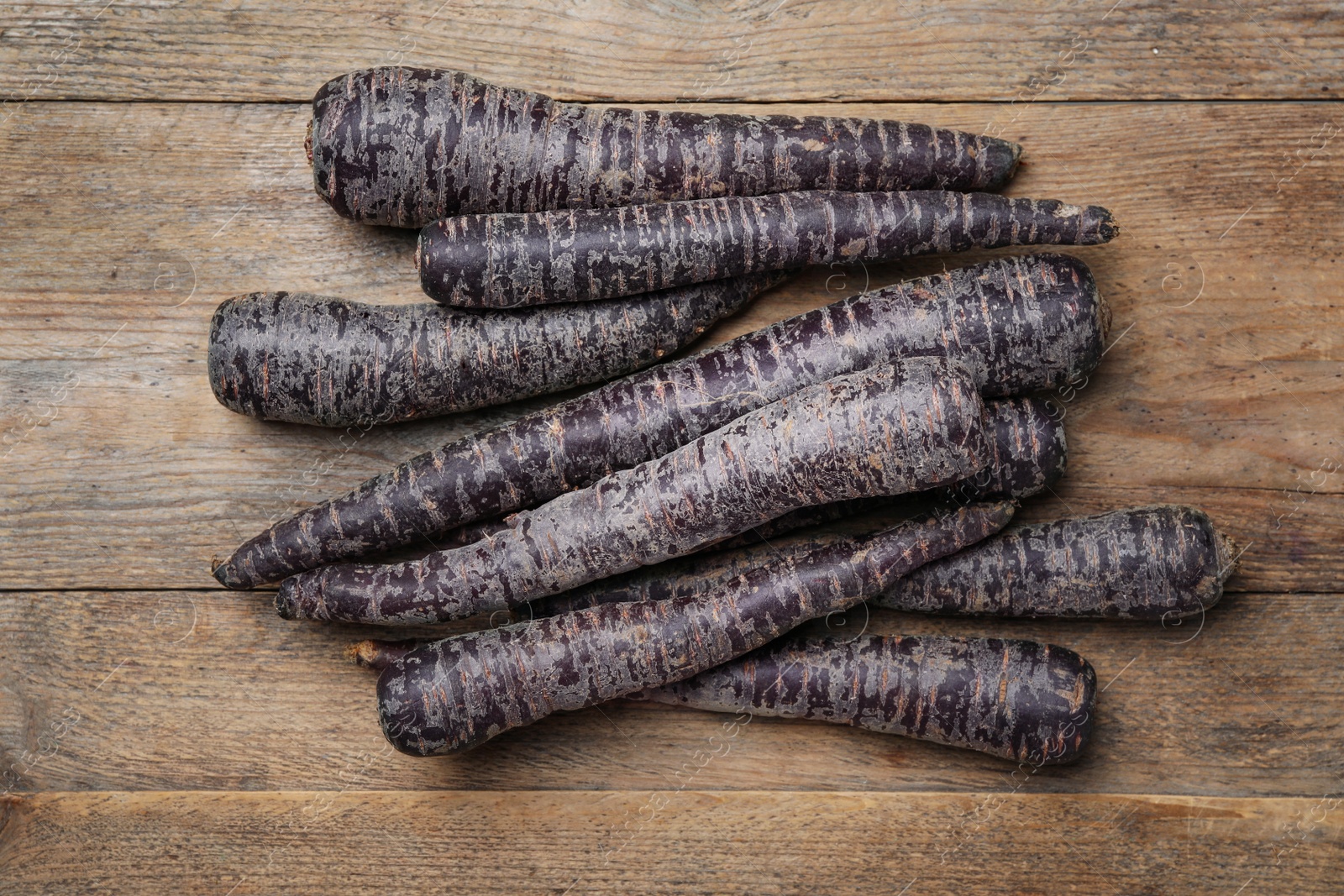 Photo of Raw black carrots on wooden table, flat lay