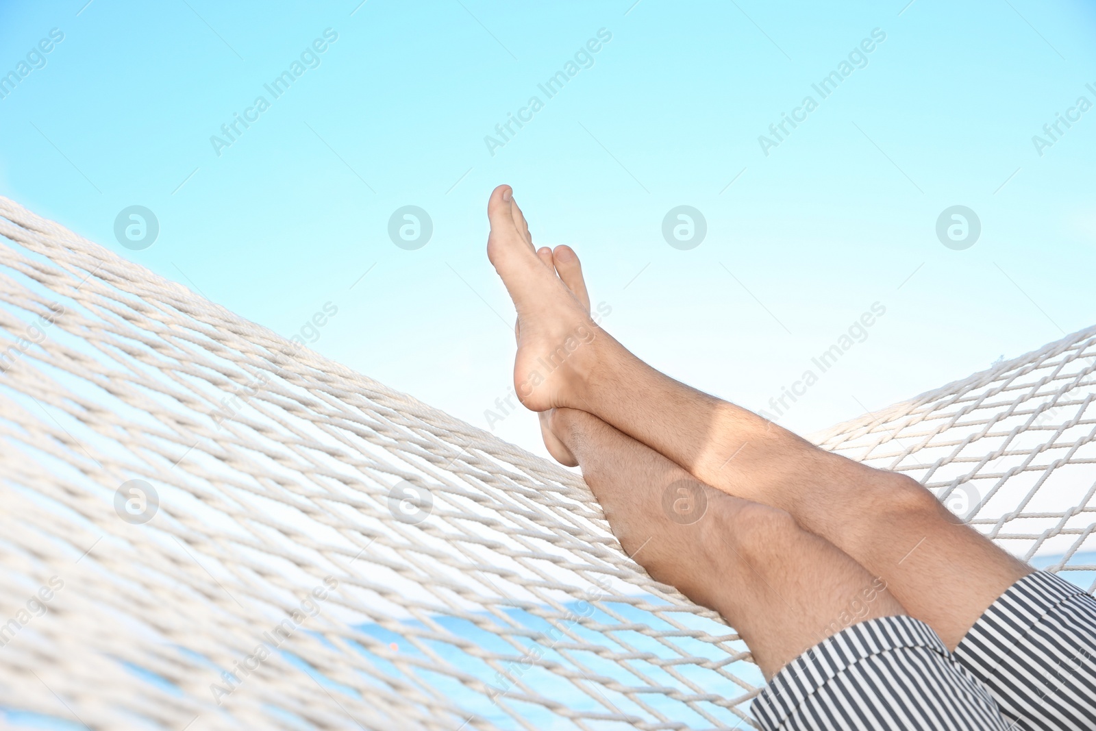 Photo of Young man resting in hammock at seaside. Summer vacation