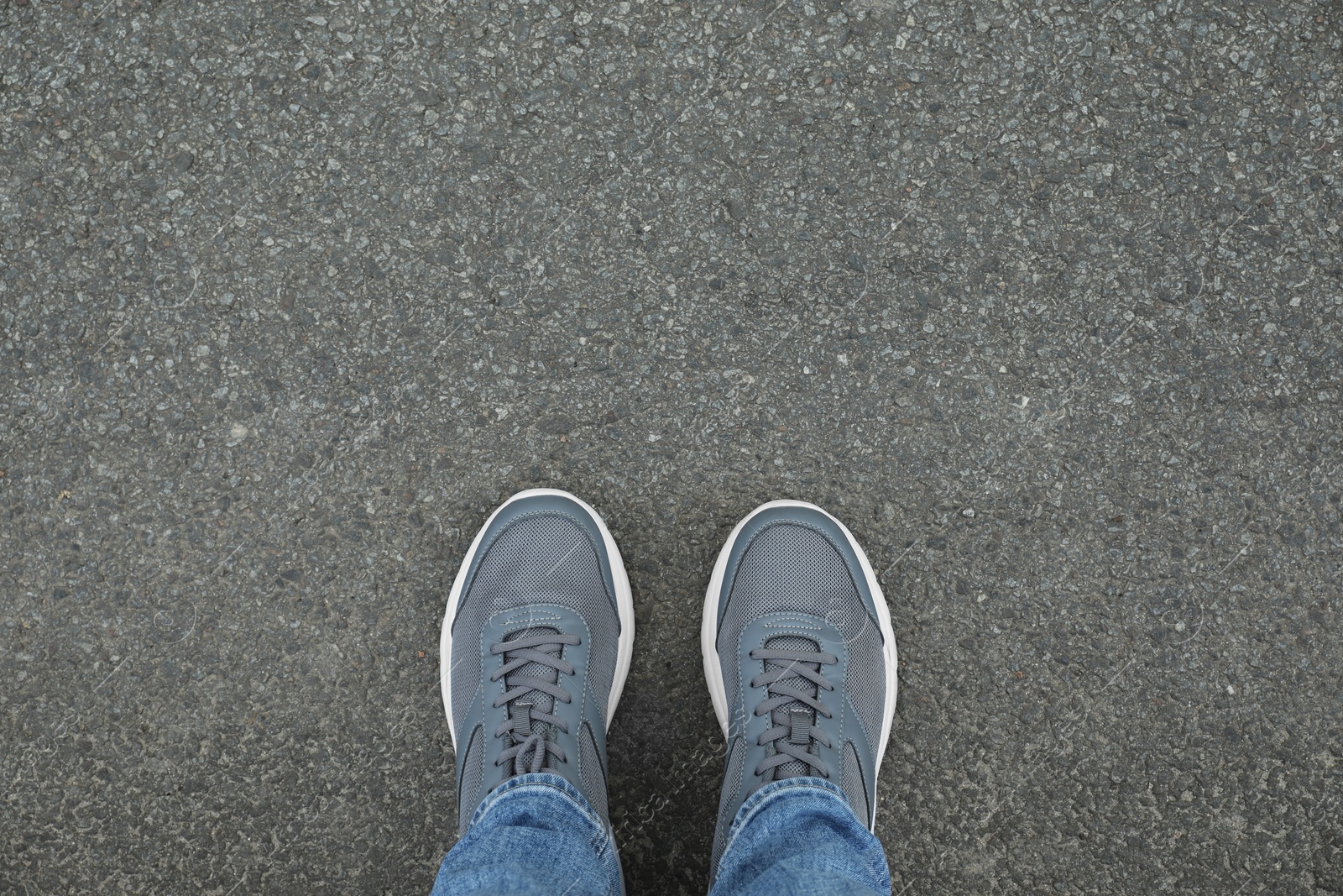 Photo of Man in sneakers standing on asphalt, top view. Space for text