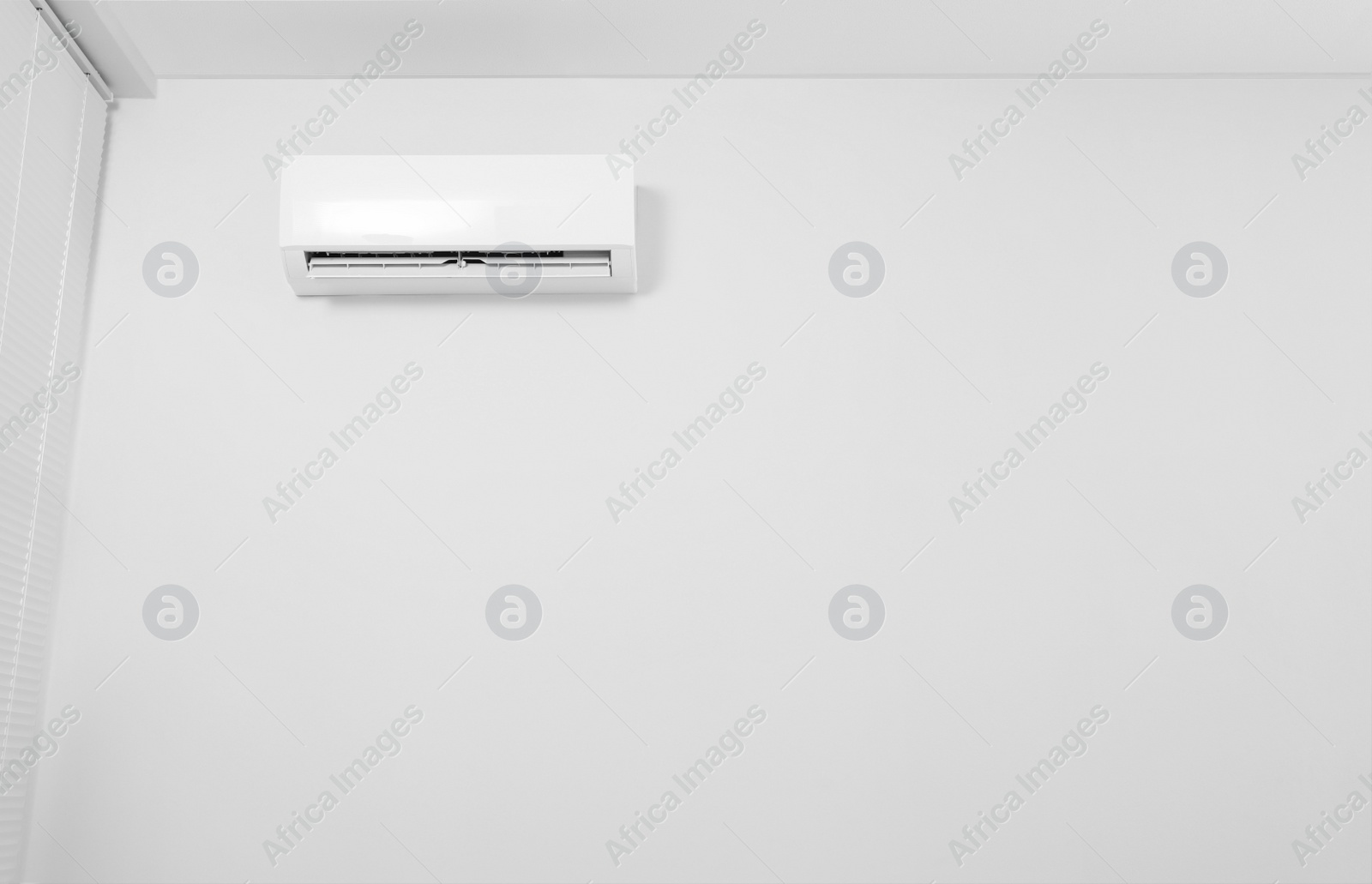 Photo of Modern air conditioner on white wall indoors. Space for text