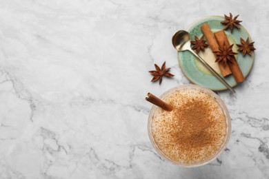 Photo of Delicious eggnog with anise and cinnamon on white marble table, flat lay. Space for text