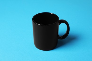 Photo of One black ceramic mug on light blue background