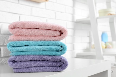 Photo of Stack of fresh towels on table in bathroom. Space for text