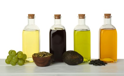 Photo of Vegetable fats. Bottles of different cooking oils and ingredients on wooden table against white background