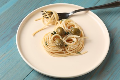 Photo of Heart made of tasty spaghetti, fork, olives and cheese on light blue wooden table
