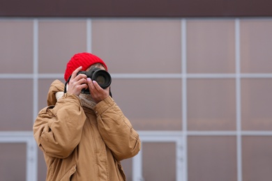 Photo of Photographer taking photo with professional camera outdoors. Space for text