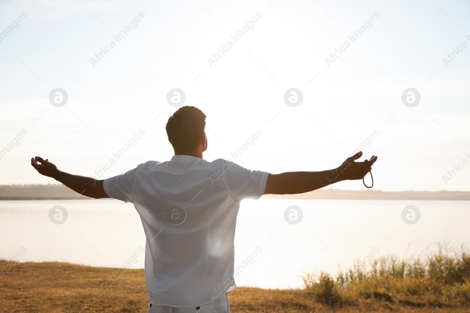 Photo of Man near river at sunset, back view. Nature healing power