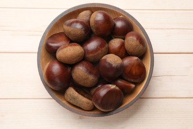 Photo of Sweet fresh edible chestnuts on light wooden table, top view