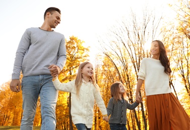 Photo of Happy family with little daughters walking in autumn park, low angle view