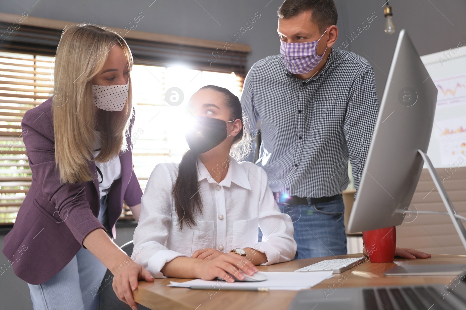 Photo of Coworkers with masks in office. Protective measure during COVID-19 pandemic