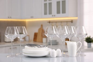 Photo of Set of clean dishware, glasses and cutlery on table in kitchen