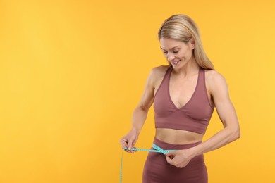 Photo of Slim woman measuring waist with tape on yellow background, space for text. Weight loss