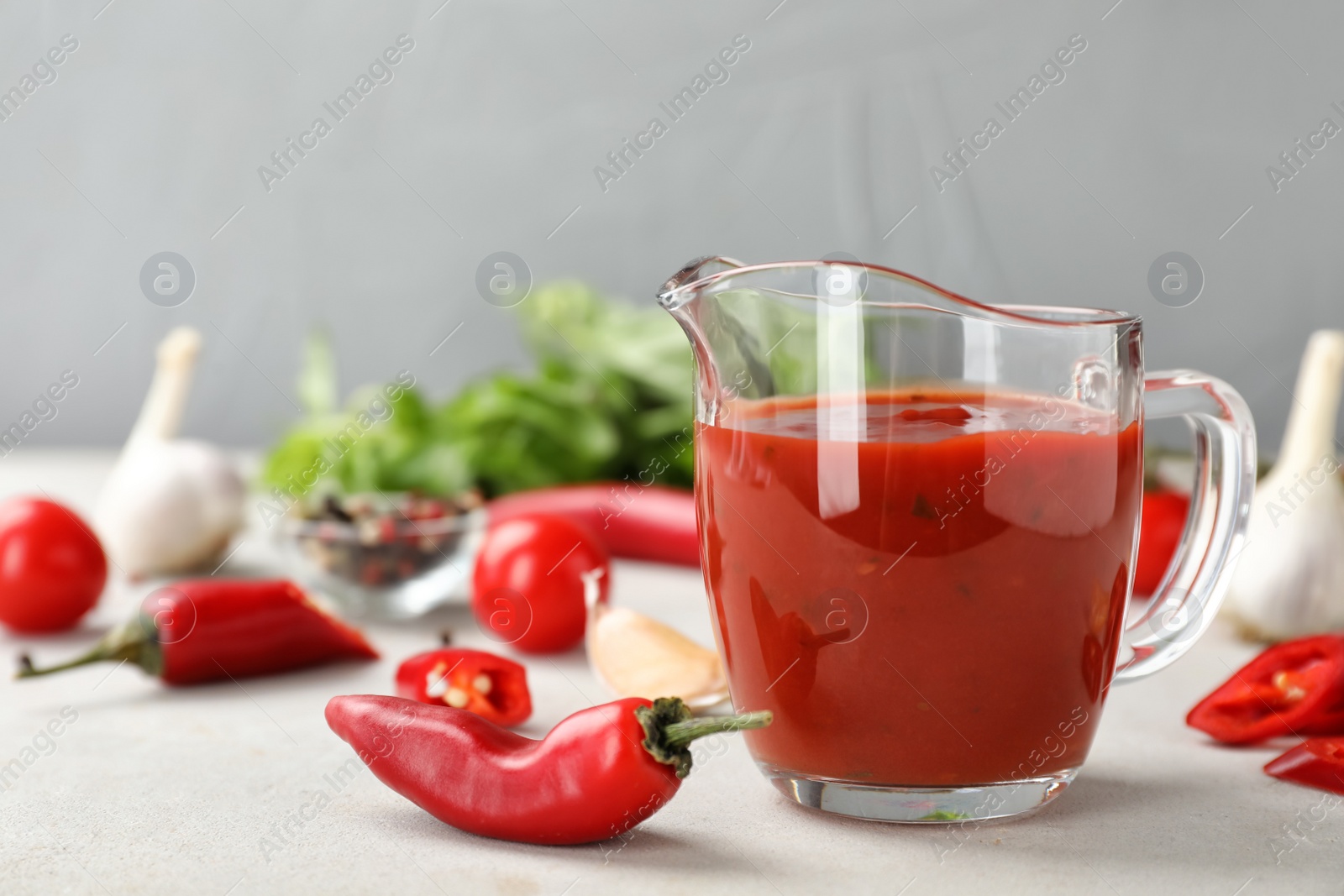 Photo of Jug with spicy chili sauce on light table