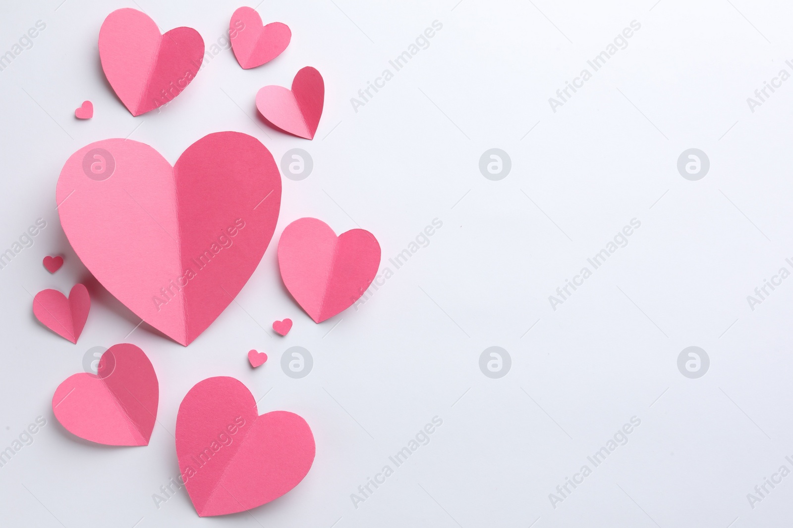 Photo of Pink paper hearts on white background, flat lay. Space for text