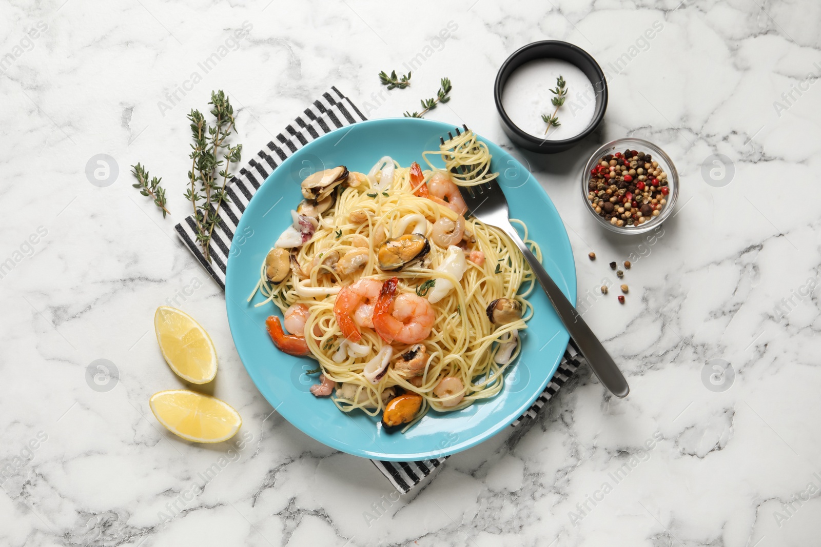 Photo of Delicious pasta with sea food served on white marble table, flat lay