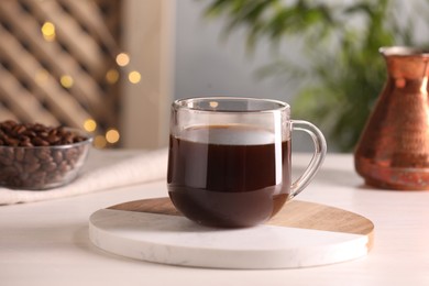 Photo of Delicious coffee in cup on white wooden table