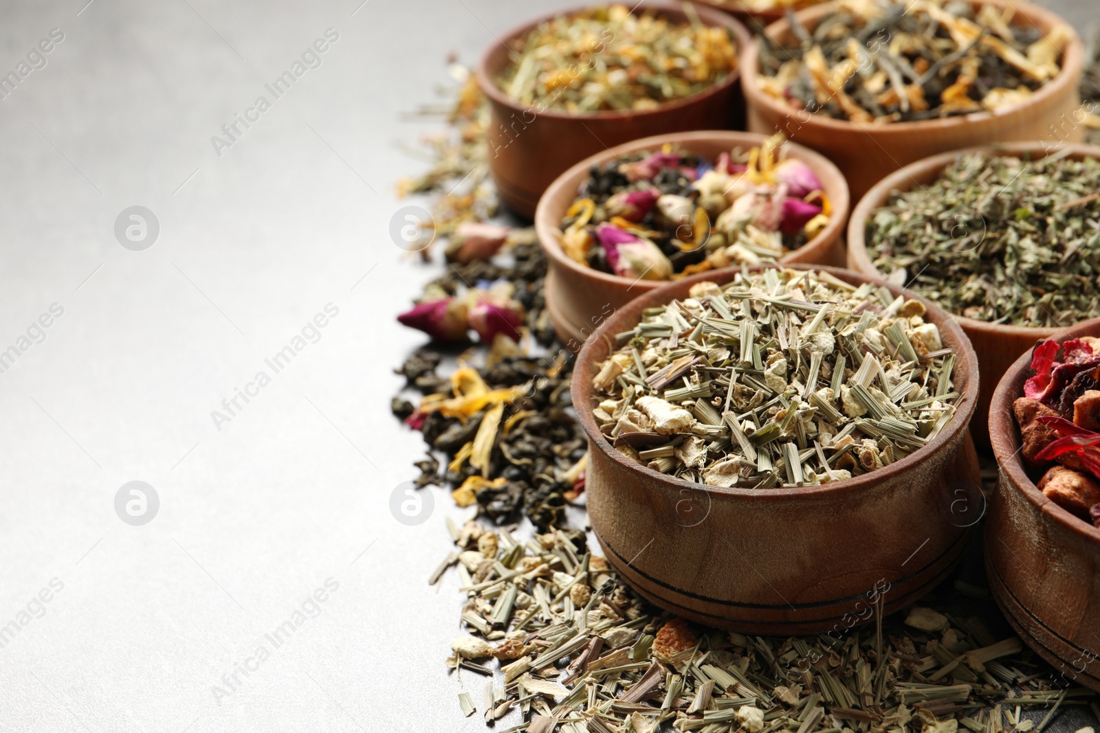 Photo of Flat lay composition with different dry teas on light grey table, space for text