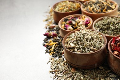 Flat lay composition with different dry teas on light grey table, space for text