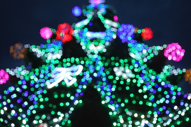 Beautiful Christmas lights on fir tree at night, low angle view. Bokeh effect