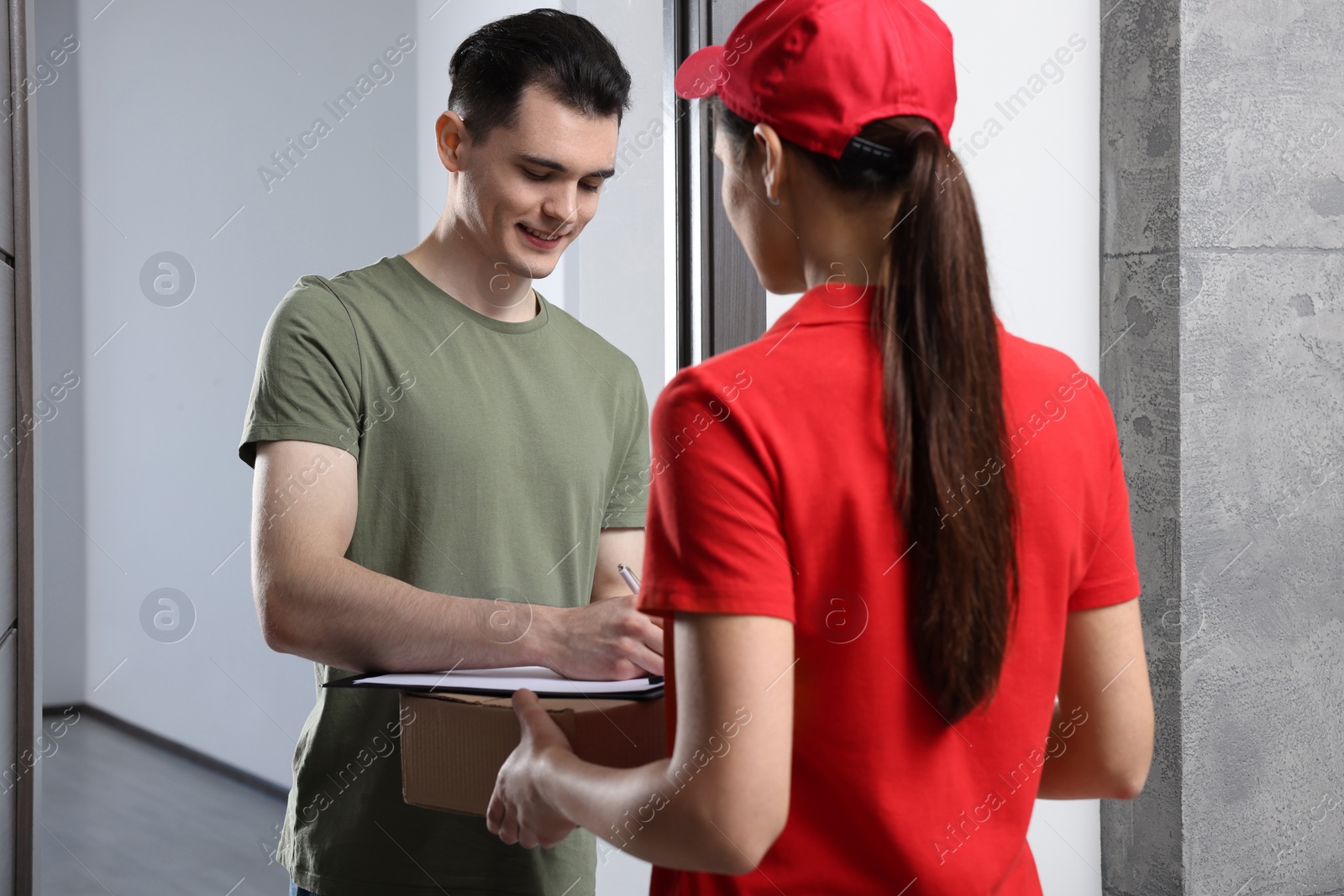 Photo of Man signing for delivered parcel from courier indoors