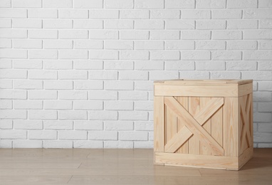 Wooden crate on floor near brick wall, space for text