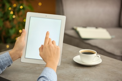 Young woman using new modern tablet at table, closeup. Space for text