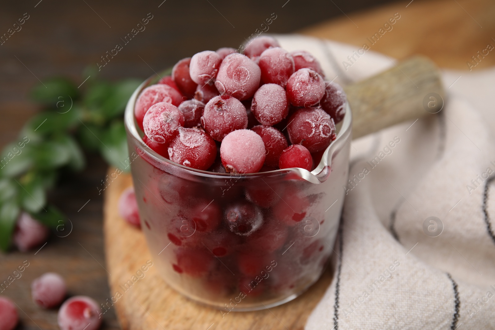 Photo of Frozen red cranberries in glass pot on table, closeup