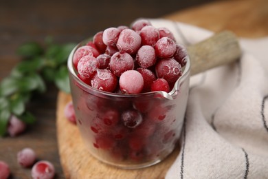 Frozen red cranberries in glass pot on table, closeup