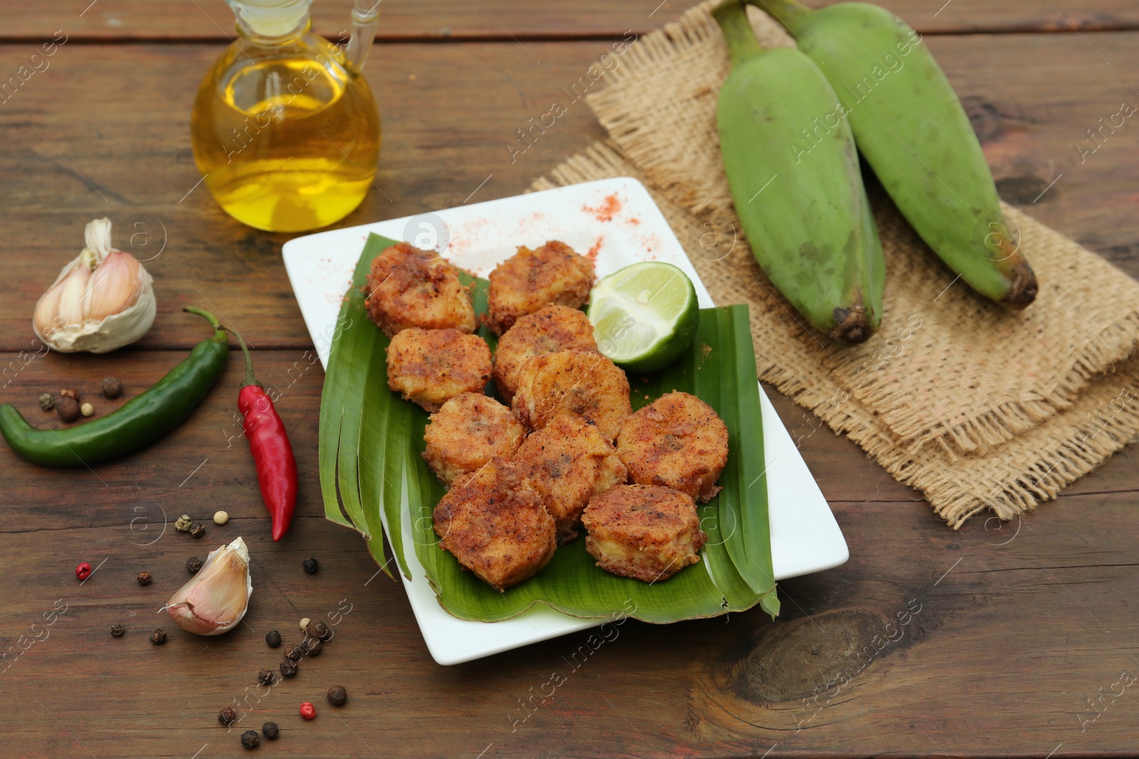 Photo of Delicious fried bananas, fresh fruits and different peppers on wooden table