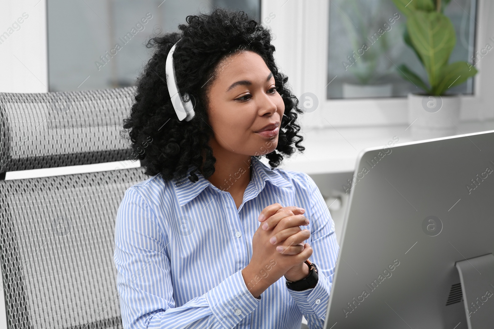 Photo of Young woman with headphones working on computer in office