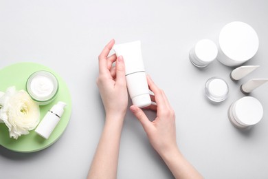 Photo of Woman holding tube of cream on light background, top view