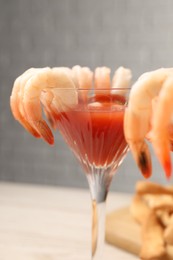 Photo of Tasty shrimp cocktail with sauce in glasses on table, closeup