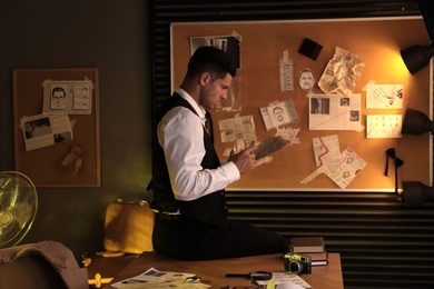 Old fashioned detective with documents near investigation board in office