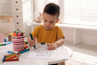 Photo of Cute child coloring drawing at table in room