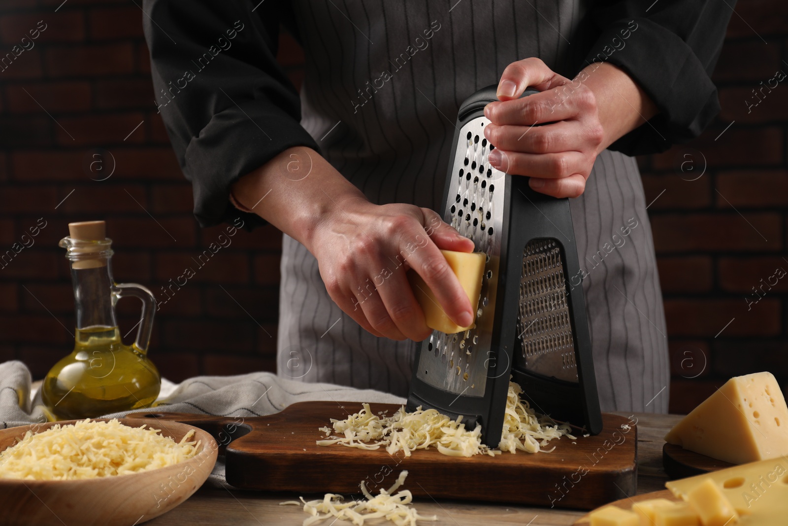 Photo of Woman grating cheese at wooden table, closeup