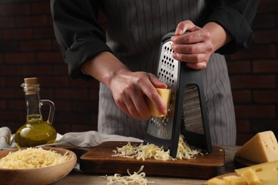 Woman grating cheese at wooden table, closeup