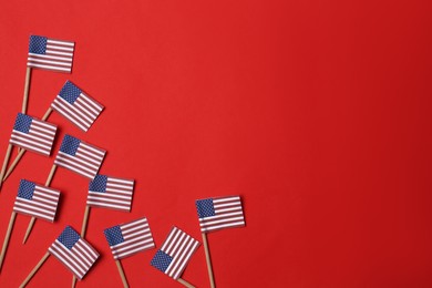 Photo of Small paper flags of USA on red background, flat lay. Space for text