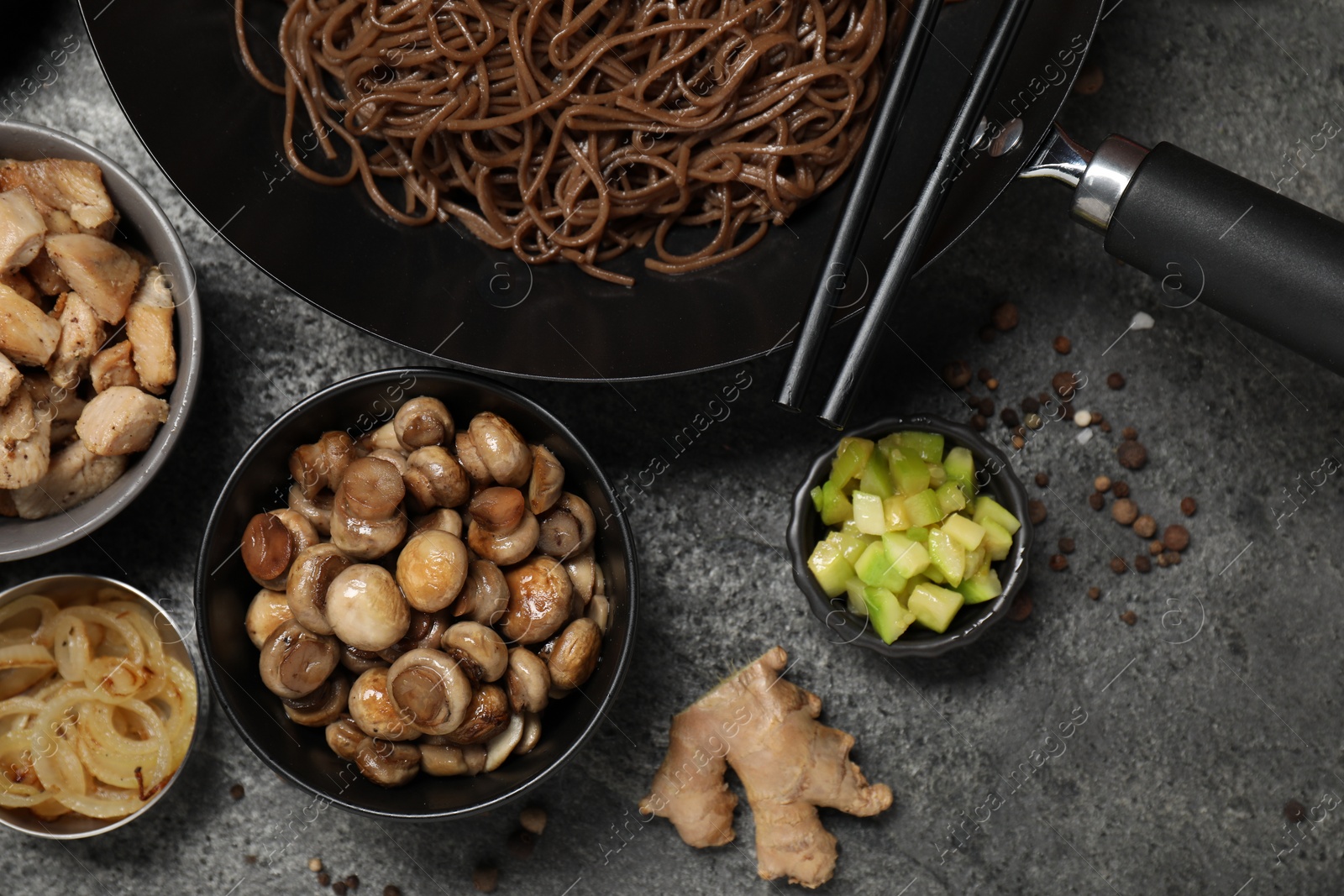 Photo of Wok with noodles, chicken and other products on grey table, flat lay