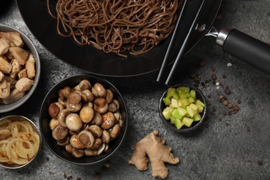 Wok with noodles, chicken and other products on grey table, flat lay