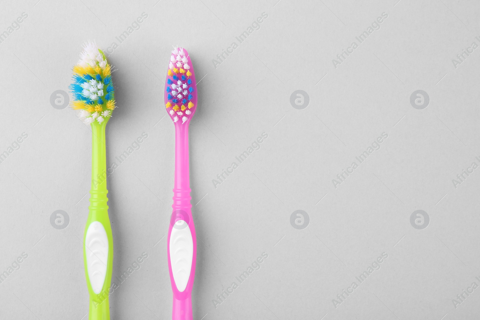 Photo of Colorful plastic toothbrushes on light background, flat lay. Space for text