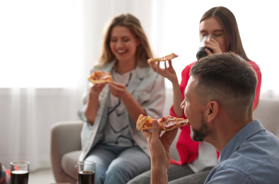 Group of friends eating tasty pizza at home