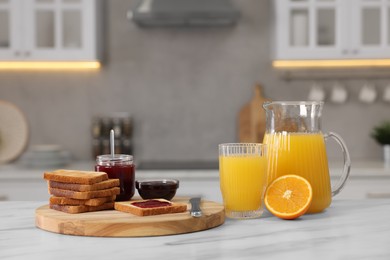 Breakfast served in kitchen. Crunchy toasts, jam and orange fresh on white table