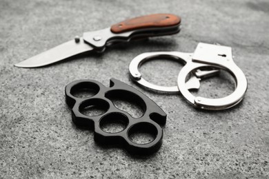 Photo of Brass knuckles, handcuffs and knife on grey background