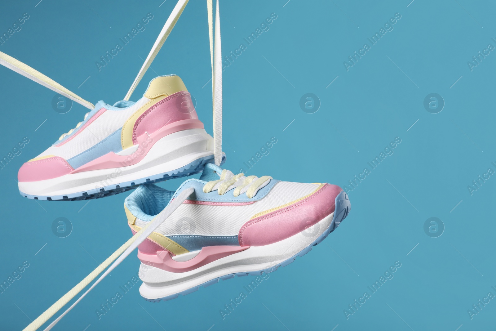 Photo of Pair of stylish sneakers on light blue background. Space for text