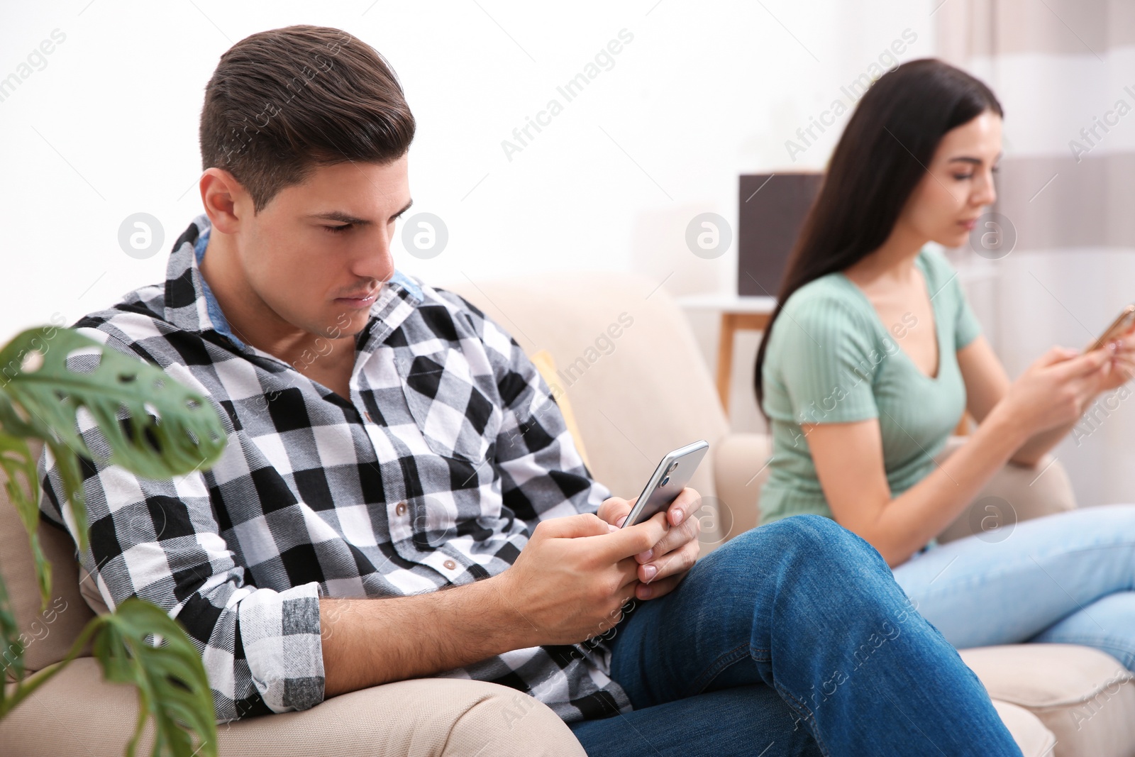 Photo of Couple addicted to smartphones ignoring each other at home. Relationship problems