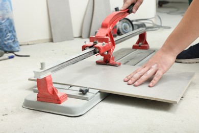 Worker using manual tile cutter indoors, closeup