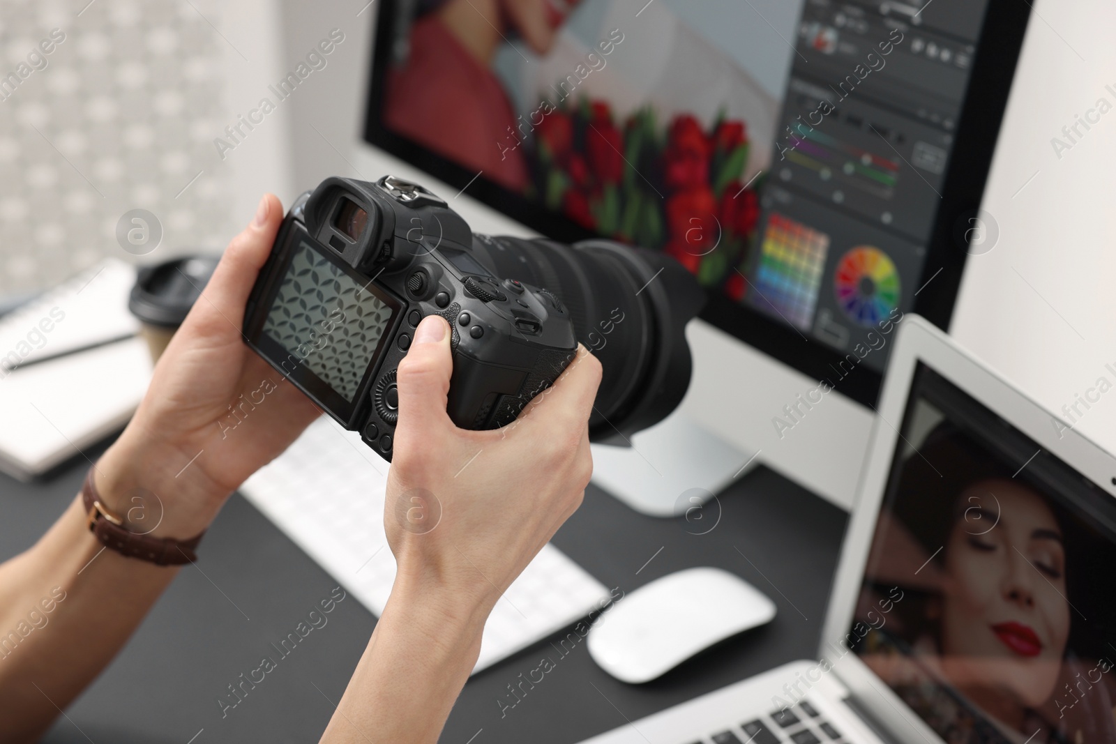 Photo of Professional photographer with digital camera at table indoors, closeup