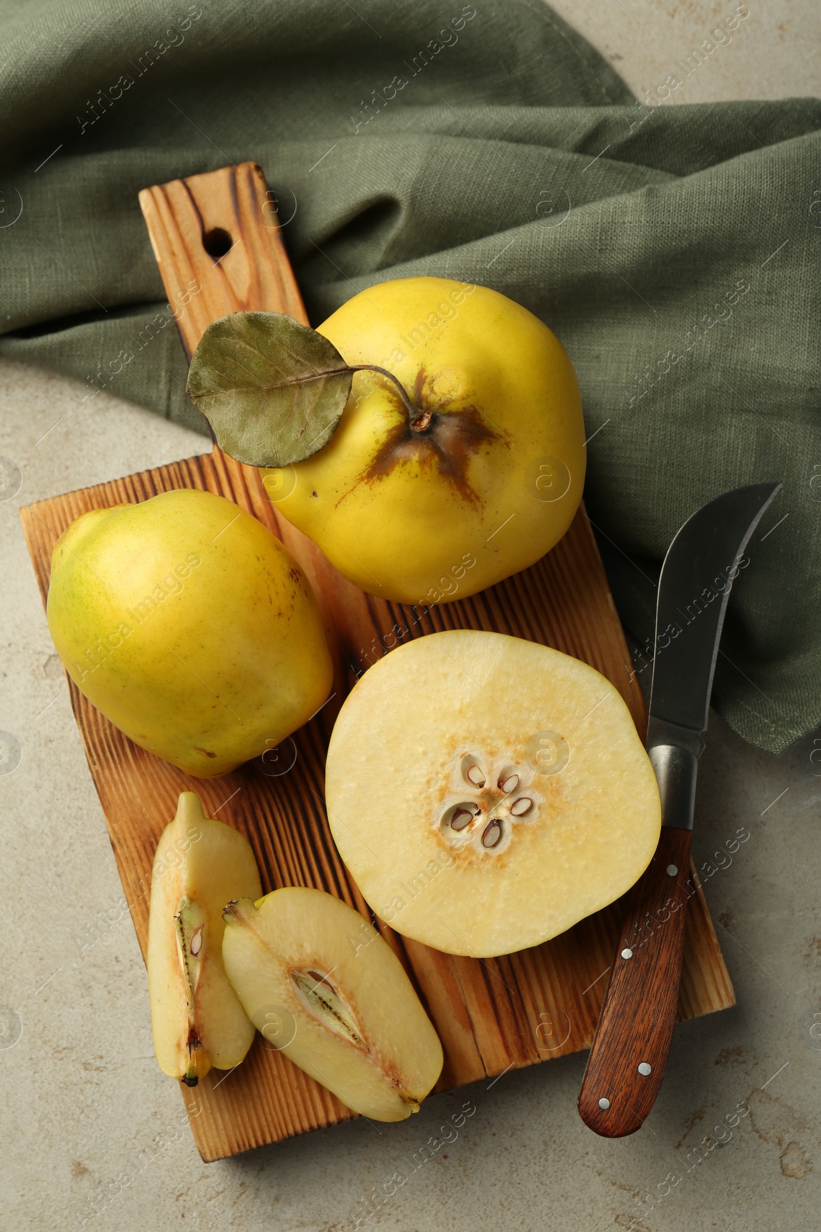 Photo of Tasty ripe quince fruits and knife on grey table, flat lay