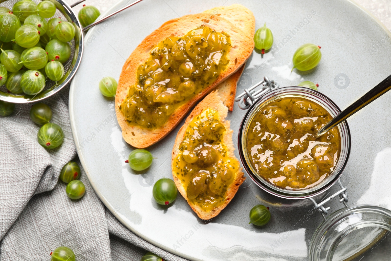 Photo of Toasts with with delicious gooseberry jam and fresh berries on table, flat lay