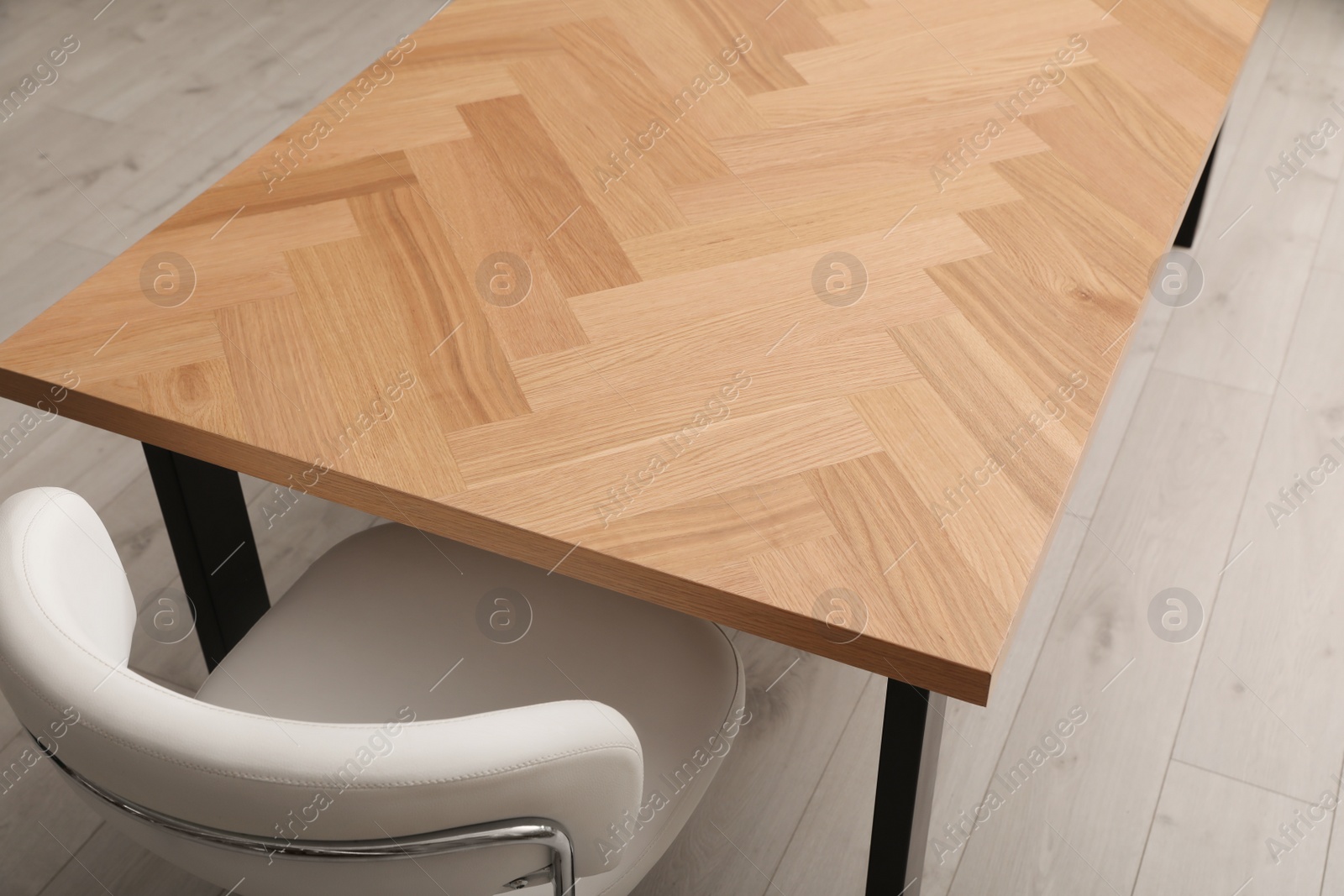 Photo of Wooden table near white office chair indoors, closeup